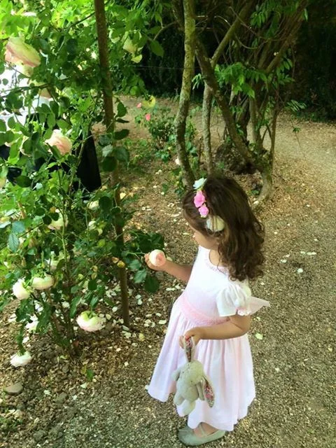 Little fairy princess in the woods wearing a handmade light pink smocked dress